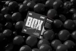 Black square box mockup resting in a pool of glossy black balls