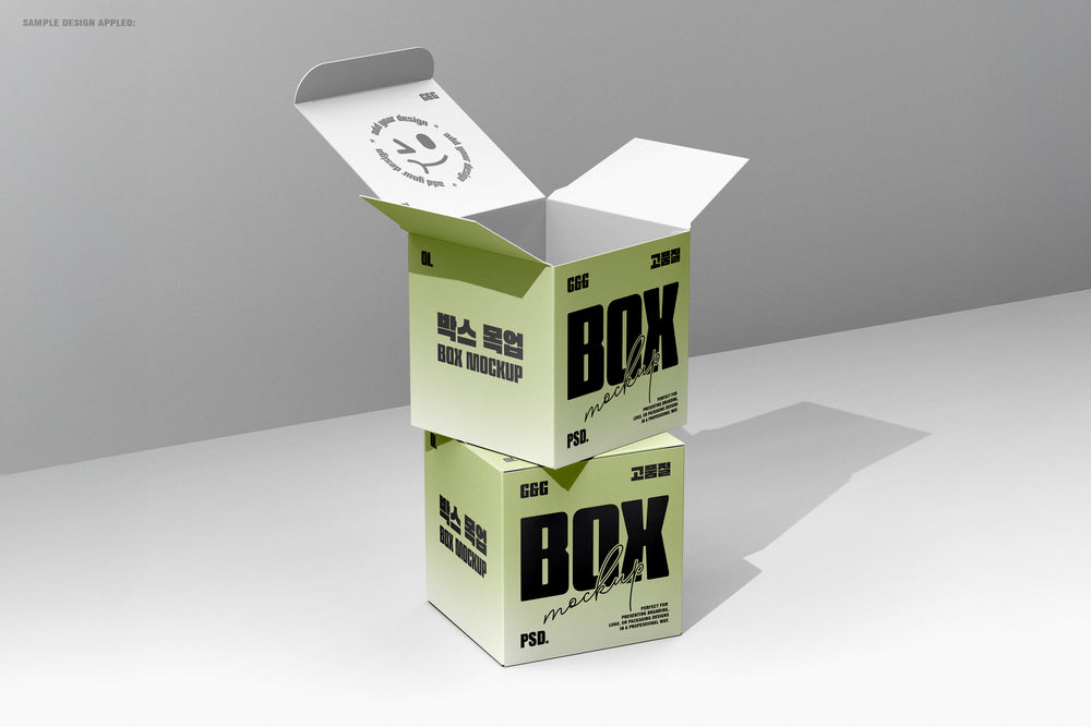 Vertical stacked square boxes, top one open showing interior print and shadow play in minimal lighting.