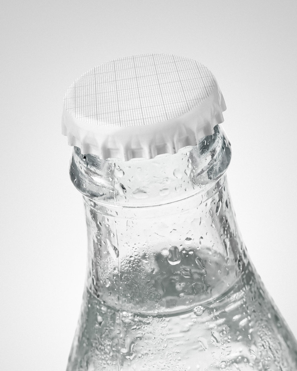 Glass bottle mockup with grid crown cap and clear water with condensation droplets