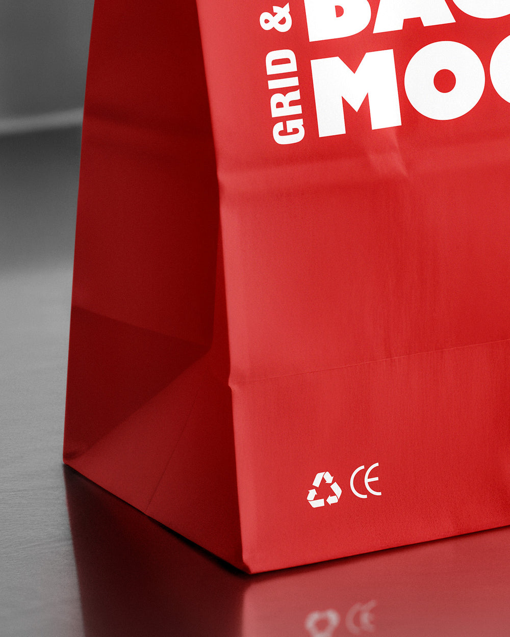 Paper bag mockup in red with reflective surface and fold-top closure macro