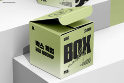 Opened green square box mockup placed on white step blocks with a second closed box in the background.